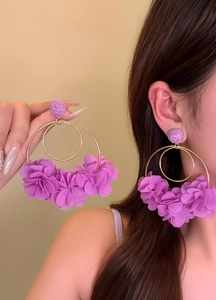 Detailed view of elegant oversized purple fabric flower hoop earrings worn by model