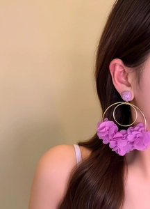 Detailed close-up of exaggerated purple fabric flower hoop earrings on an Asian model