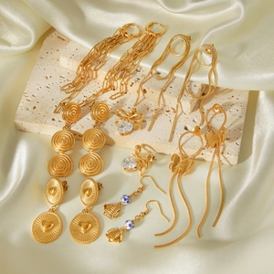 Detailaufnahme verschiedener goldener Edelstahlohrringe auf einer strukturierten Steinplatte.