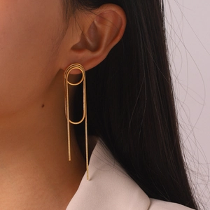 Detailansicht eleganter langer goldener Edelstahl-Quastenohrringe am Ohr eines Models.