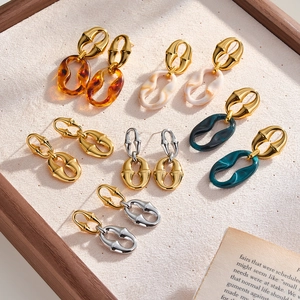 Vue détaillée de diverses boucles d'oreilles en résine et acier sur un plateau à bijoux