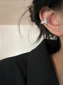 Close-up view of a sparkling zircon cross ear cuff on a model's ear, non-pierced jewelry detail