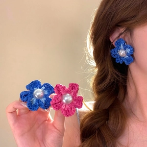 Primo piano di orecchini a fiore all'uncinetto blu e rosa fatti a mano con perle