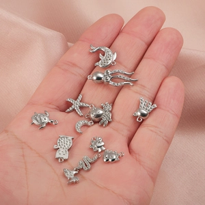 Variété de breloques d'animaux en acier inoxydable argenté tenues à la main pour bijoux