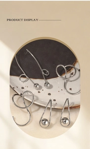 Detail view of various creative silver stainless steel geometric earrings on a plate
