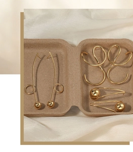 Detailed macro view of creative geometric stainless steel gold earrings in a recycled tray