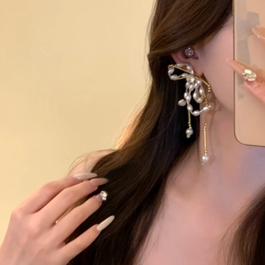 Detail shot of pearl bow earrings with long tassel on model
