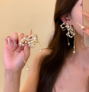 Detail view of elegant bow-shaped pearl earrings with zircon accents shown on a model