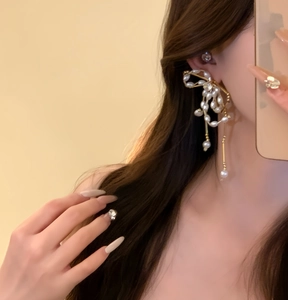 Close-up detail of elegant bow-shaped earrings featuring pearls and sparkling zircons