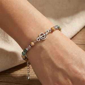 Close-up of beaded music bracelet with a silver treble clef charm worn on a model wrist