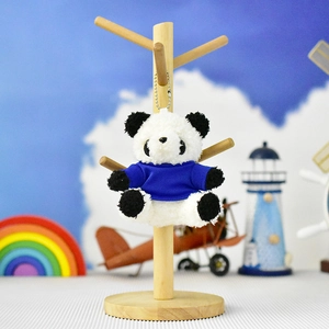 Cute plush panda keychain wearing a royal blue shirt hanging on a decorative wooden stand