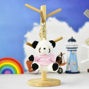 Detailed view of a cute panda plush keychain wearing a pink shirt on a wooden display stand