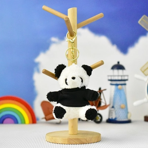 Detailed view of a small plush panda keychain wearing a black sweater hanging on a stand