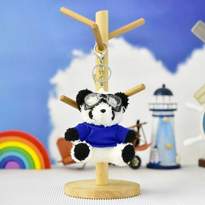 Cute plush panda keychain with blue shirt and pilot goggles on display stand