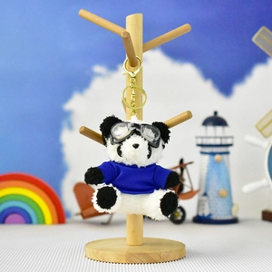 Close-up of plush panda keychain wearing blue shirt and aviator goggles