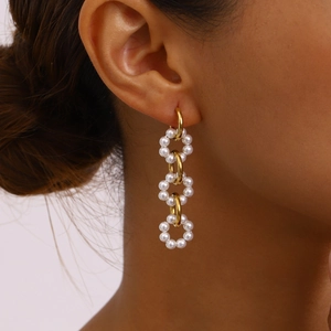 Macro detail of elegant 18K gold chain hoop earrings with white pearls for women