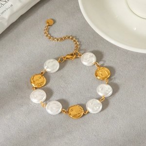 Detail view of a retro stainless steel bracelet with white pearls and gold discs