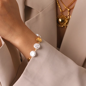 Detail of a vintage-style stainless steel bracelet featuring flat pearls and gold discs.