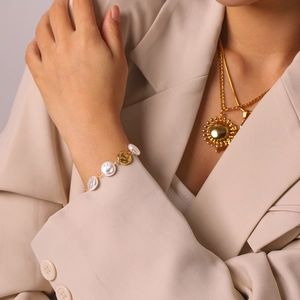 Close-up of stainless steel pearl bracelet with sun pendant necklace on a model