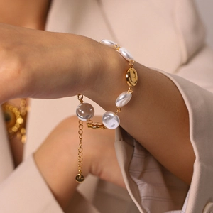Elegant close-up detail of stainless steel bracelet with baroque pearls and golden discs