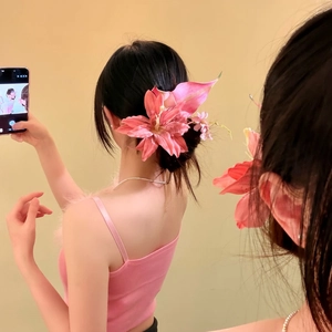 Elegant pink oversized lily flower hair clip worn by woman for summer holiday styling.
