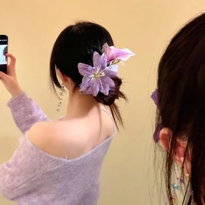 Detailed view of oversized purple flower hair clip styled on an elegant low bun hairstyle.