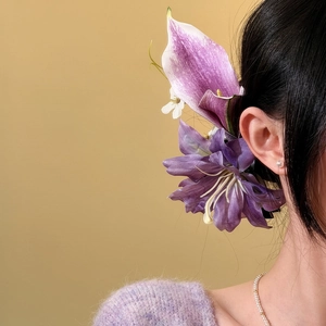 Close-up of a model wearing an oversized purple floral hair clip for a vacation look