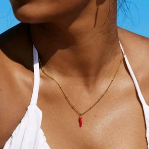 Close-up of a 18K gold beaded necklace with a glossy red chili pendant on a model