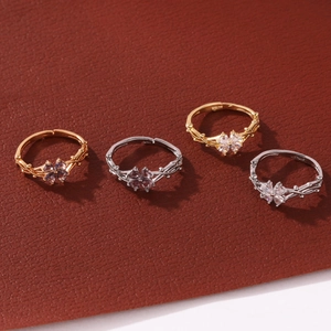 Elegantes anillos de trébol minimalistas con circonitas brillantes en fondo de cuero