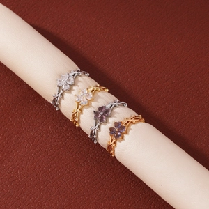 Detalle de cuatro anillos de flores de trébol con circonitas moradas y blancas en soporte
