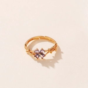 Vista detallada de un anillo de trébol dorado con cuatro circonitas moradas de corazón