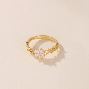 Detalle de un anillo dorado con trébol de cuatro hojas de circón y banda tipo liana.