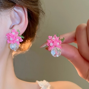 Macro detail shot of handmade pink beaded flower earrings with a clear crystal bead.
