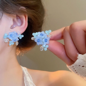 Detailed macro view of blue forest-style flower stud earrings with crystal bead accents