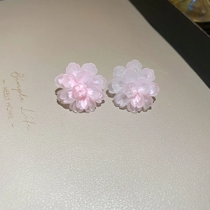 Macro detail of light pink translucent resin flower earrings with multi-layered petals.