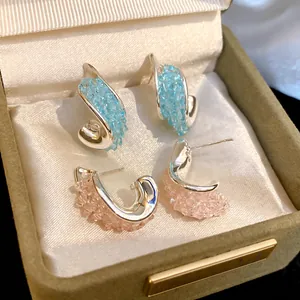 Elegante gedrehte Silberohrringe mit hellblauen und rosa Kristallen in einer Box