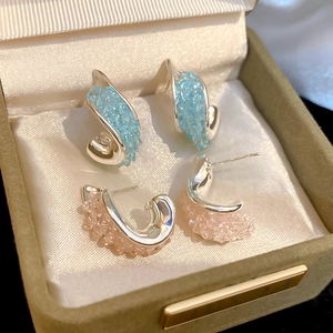 Nahaufnahme von gedrehten Silberohrsteckern mit blauen und rosa Kristallen in Box