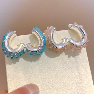 Nahaufnahme der gedrehten Kristall-Ohrringe in Blau und Rosa mit stacheliger Textur.