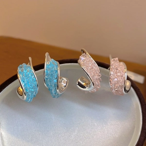 Detailansicht funkelnder blau-rosa gedrehter Kristall-Ohrstecker auf einem Display.