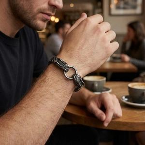 Close-up of vintage steel dragon head bracelet for men on wrist in a cafe setting