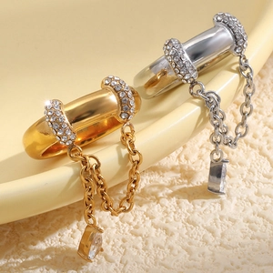 Détail d'une bague en acier inoxydable avec chaîne à pompons, goutte en zircon et strass