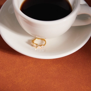 Detailed view of a gold plated stainless steel zircon open ring on a white saucer