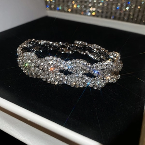 Gros plan d'un élégant bracelet tressé en strass argentés sur un support en velours noir