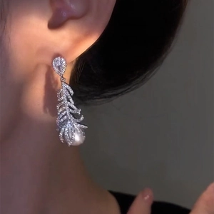 Detail view of elegant feather earrings with micro-pave zircons and a pearl drop