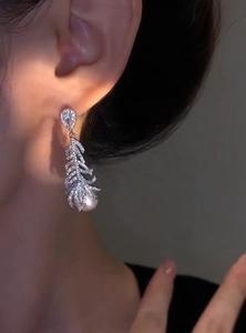 Macro view of exquisite feather-shaped pearl earring with micro-pave cubic zirconia