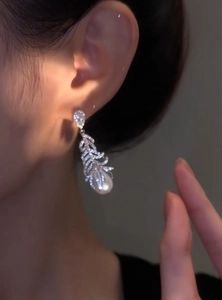 Elegant micro-pave zircon feather earrings with pearl drops shown on model's ear