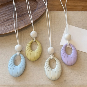 Detailed view of colorful oval pendant necklaces in blue, yellow, white, and purple.