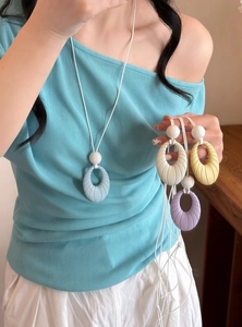 Close-up of pastel oval pendant necklaces in multiple colors on a female model