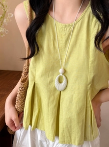 Close-up of white oval ribbed pendant necklace worn with a lime green linen top