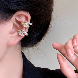 Macro view of gold-colored zircon-encrusted snake-shaped ear cuff on a model's ear